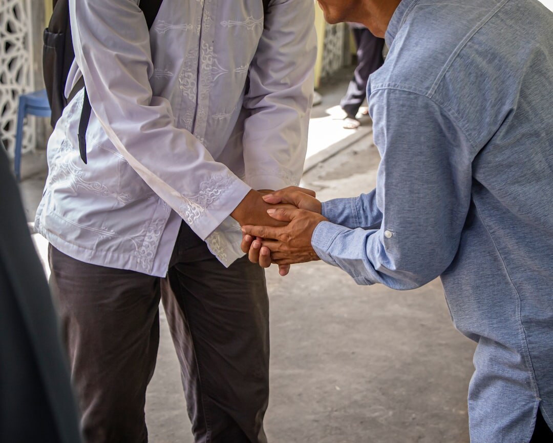Senior man and community coordinator shaking hands over a membership form